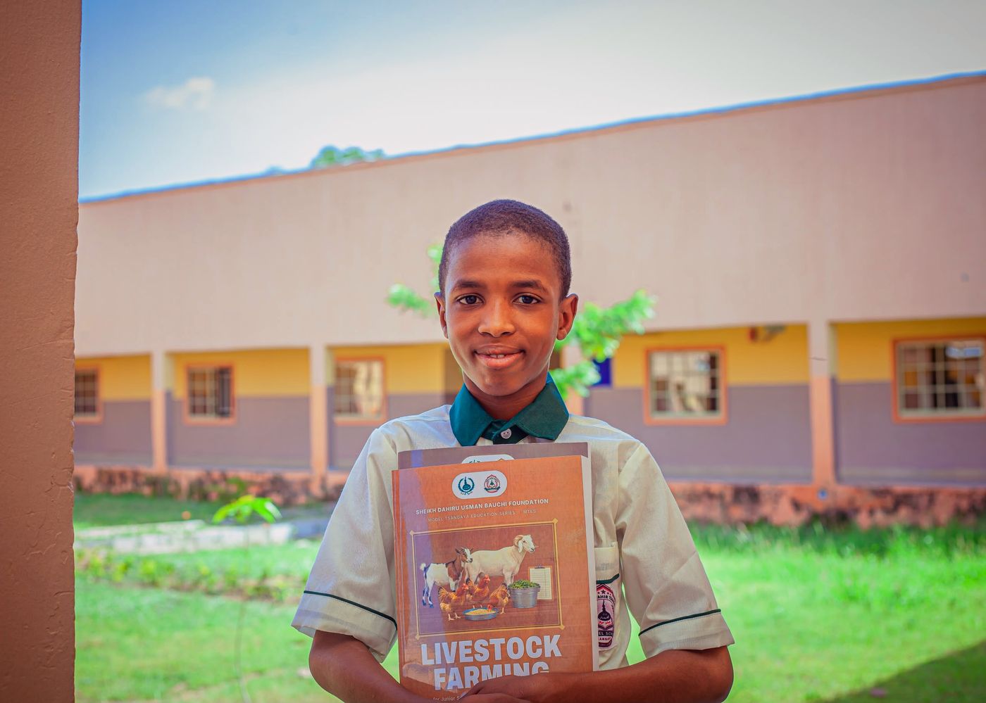 A smiling pupil holding his Livestock Farming book